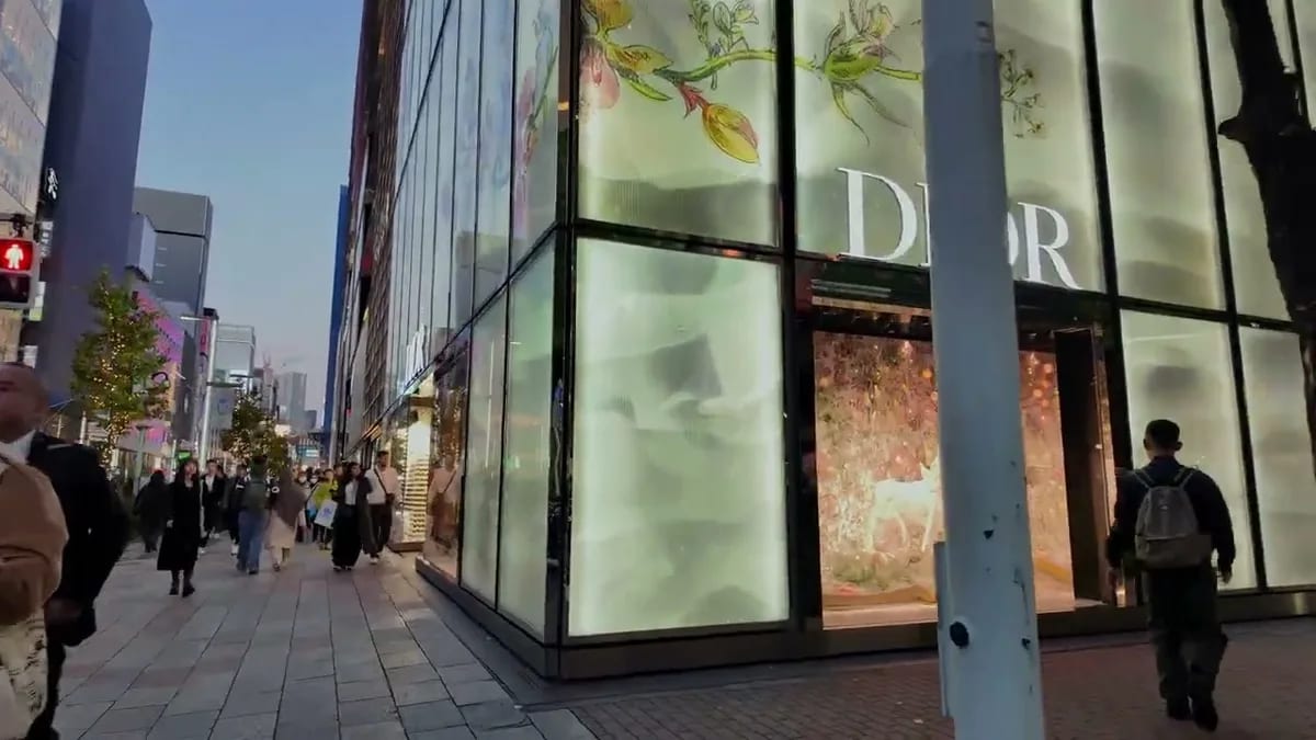 Exterior of the Dior luxury store in Ginza, Tokyo, Japan, with illuminated floral displays and pedestrians at dusk.