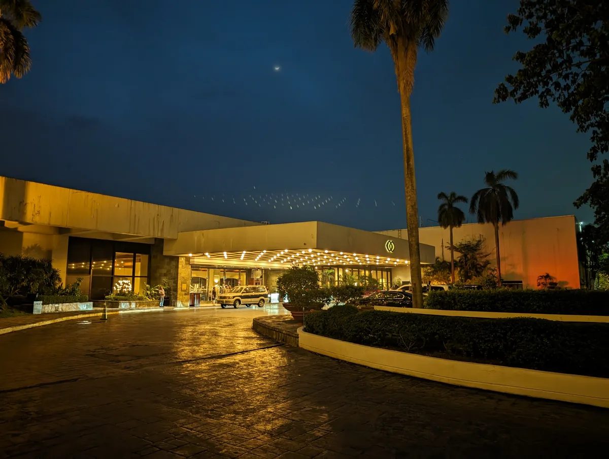 Sofitel Philippine Plaza hotel entrance at dusk with warm lights, a vintage car, and palm trees in Pasay, Metro Manila.