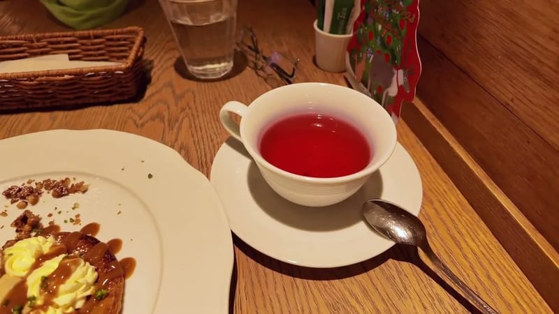 Close-up of a cup of red fruit tea next to a cream and nut dessert on a wooden table at Afternoon Tea in Tokyo Skytree Town, Japan