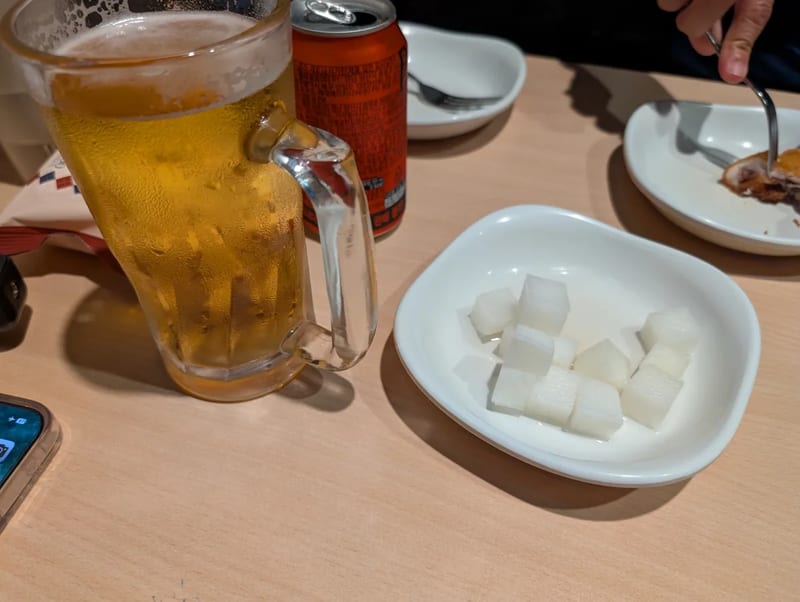A frosty mug of Korean draft beer next to a dish of pickled radish cubes
