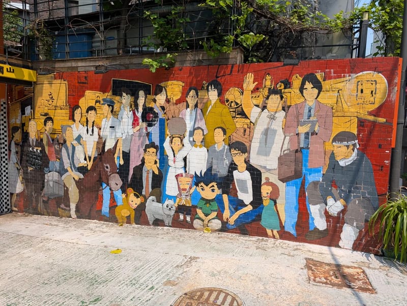 A large street mural of a crowd of people painted on a brick wall