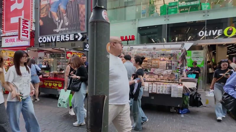 Busy Myeongdong shopping street with crowds, an Olive Young store and a street dumpling vendor