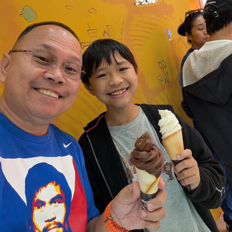Selfie with my son holding chocolate and vanilla soft serve cones at an ice cream shop