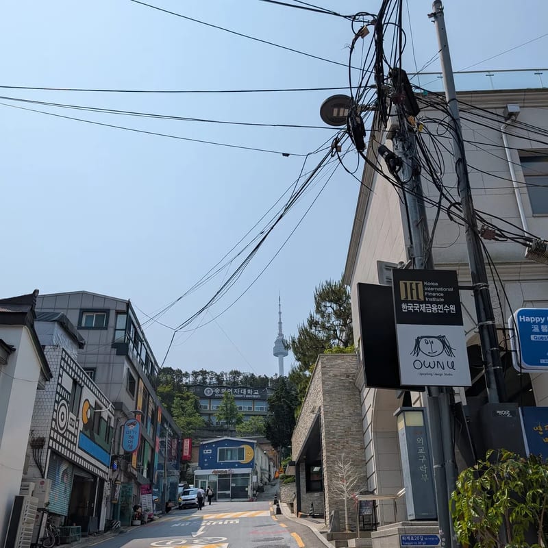 A Namsan-dong side street climbing toward N Seoul Tower under tangled power lines