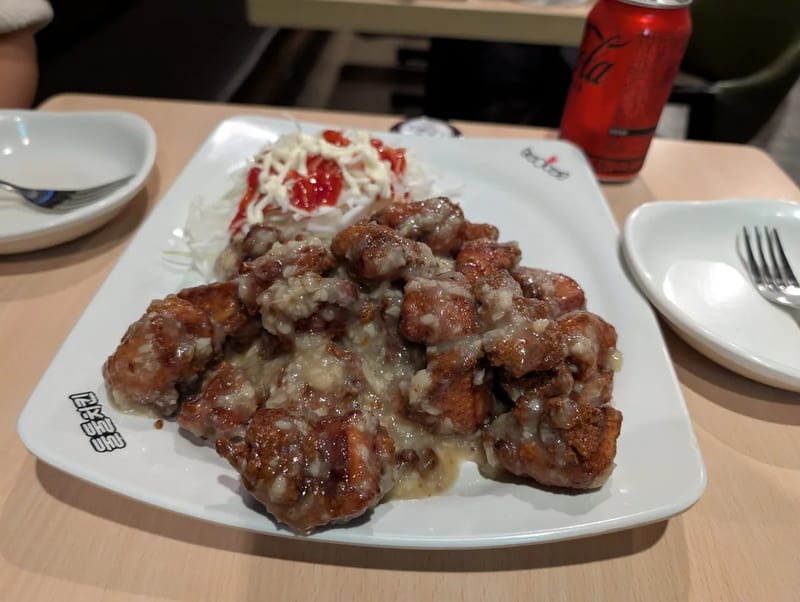 A second plate of Korean fried chicken in a creamy onion sauce with coleslaw on the side
