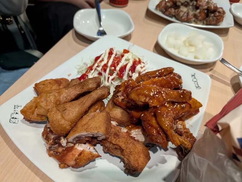 A plate of Korean fried chicken, half plain fried and half sweet and spicy glazed, with coleslaw and pickled radish