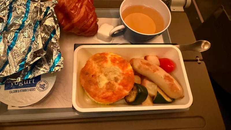 Airplane breakfast with baked egg, sausage, croissant and tea