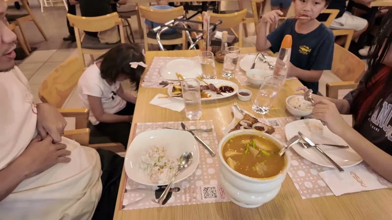 Family eating rice, grilled meats and sinigang at Mesa restaurant