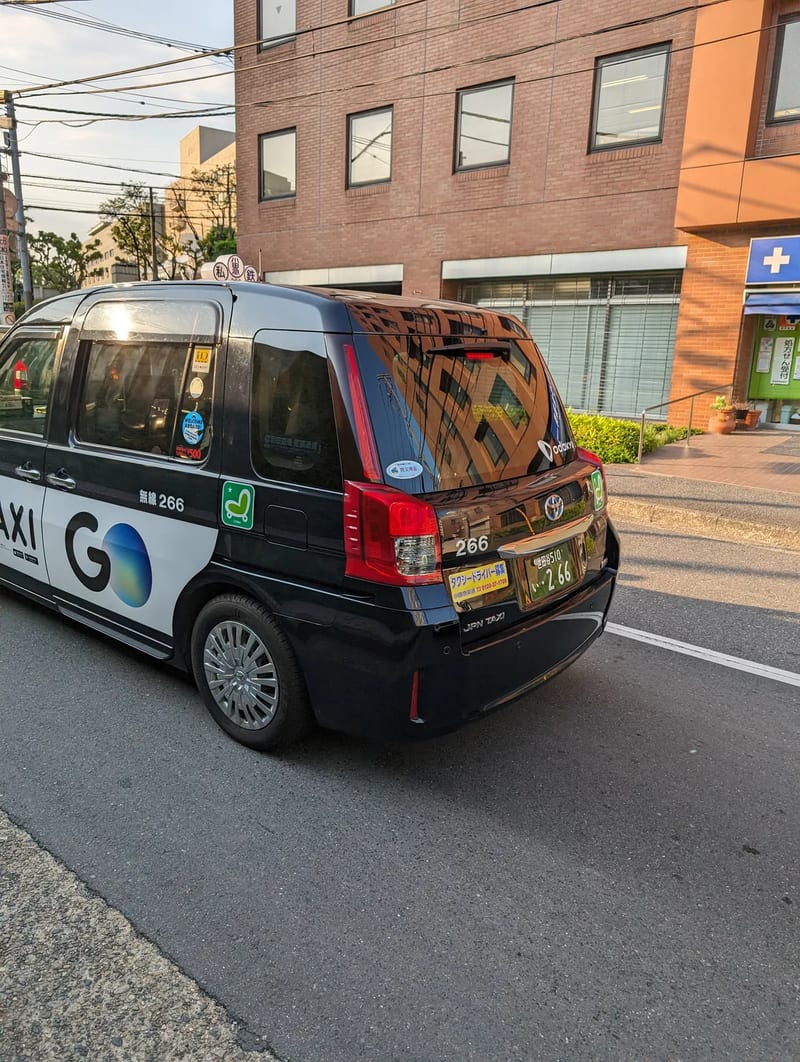 Rear view of a black GO TAXI branded Toyota Sienta taxi in Shibuya, Tokyo, Japan.