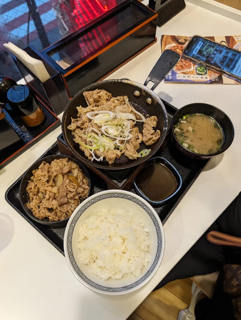 Japanese meal set with sizzling pork, beef and rice bowl, and miso soup at Yoshinoya in Shibuya, Tokyo, Japan.
