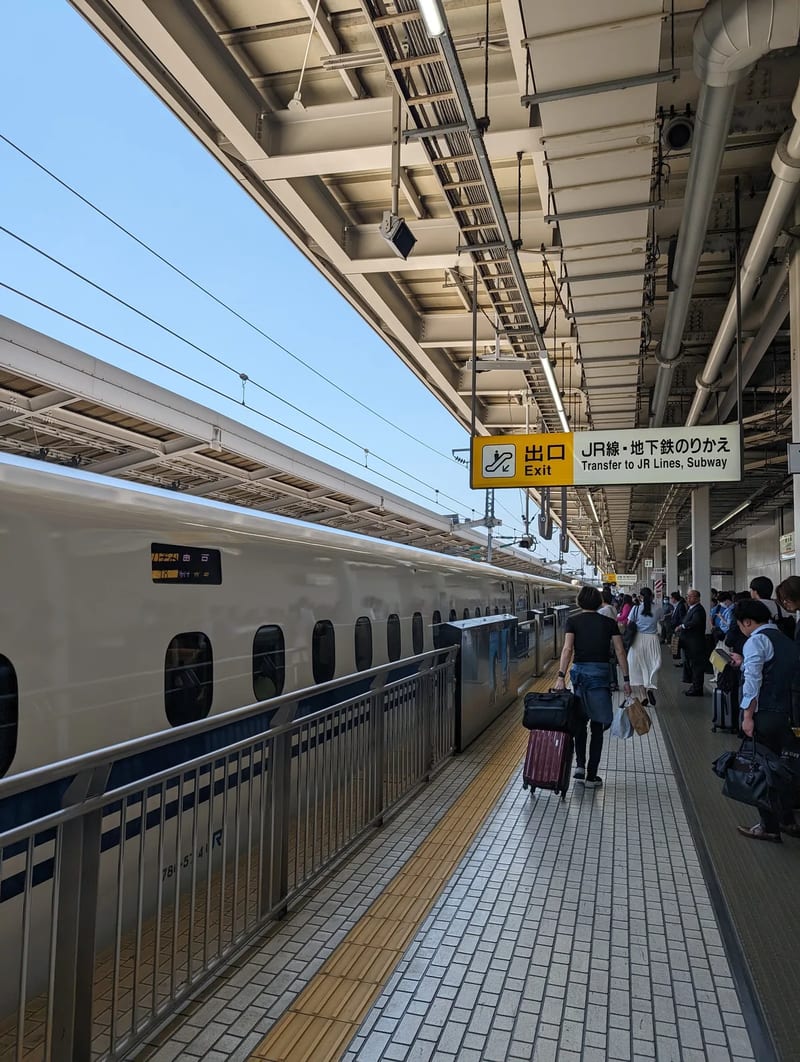 Shinkansen bullet train at Shin-Osaka Station platform with 'Exit Transfer to JR Lines, Subway' sign, Japan.