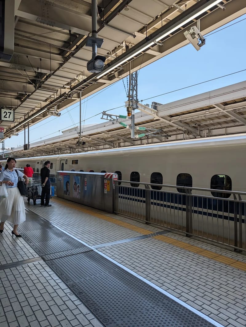 Shinkansen bullet train at Shin-Osaka Station platform with people waiting, Japan.