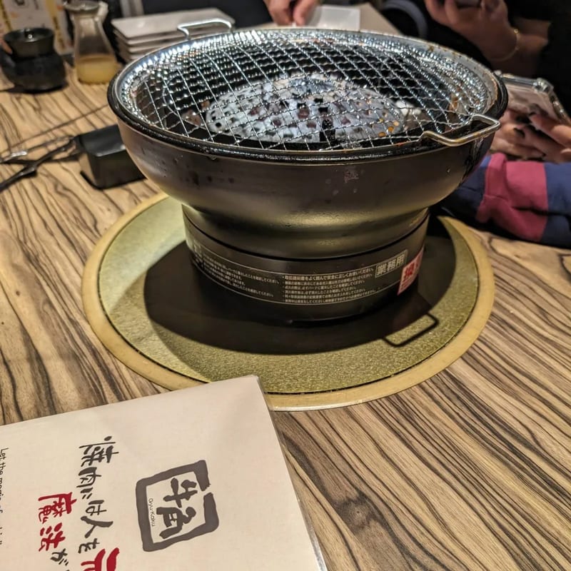 Personal charcoal grill on a wooden table at a Japanese BBQ restaurant.