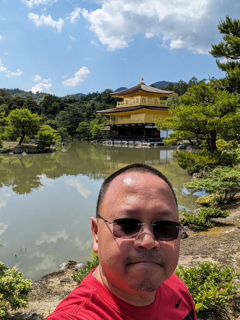 Man and child selfie in front of Kinkaku-ji Golden Pavilion in Kyoto, Japan.