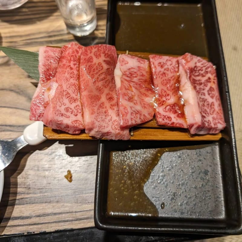 Slices of marbled raw wagyu beef on a bamboo leaf with dipping sauce in Japan.