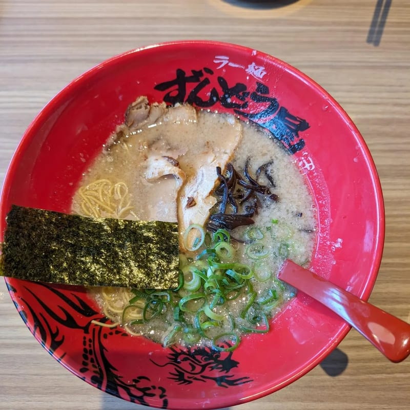 Overhead view of Tonkotsu ramen in a red bowl with pork, green onions, and egg in Japan.