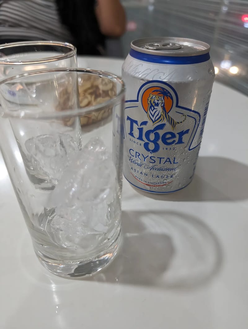 Chilled can of Tiger Crystal beer on a white table next to two glasses one filled with ice with condensation on the can at a hotel in Puerto Princesa, Palawan, Philippines