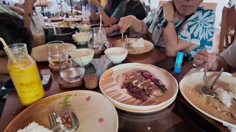 Kare-kare made with carabao, in peanut sauce Plated kare-kare in peanut sauce with rice and a mango shake across a shared table