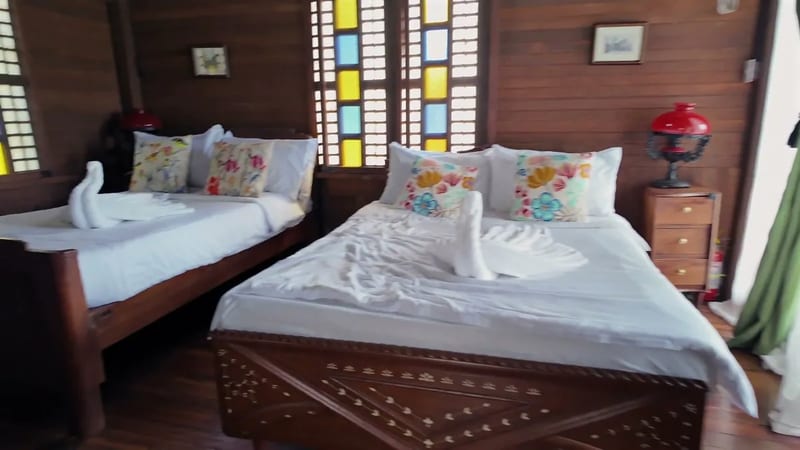 Towels folded into swans, stained glass, all wood Wooden overnight guest room with two beds, towels folded into swans and stained glass windows