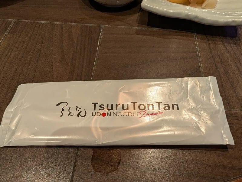 Tsuru Ton Tan udon restaurant chopstick sleeve on a dark wooden table in Shibuya, Tokyo, Japan