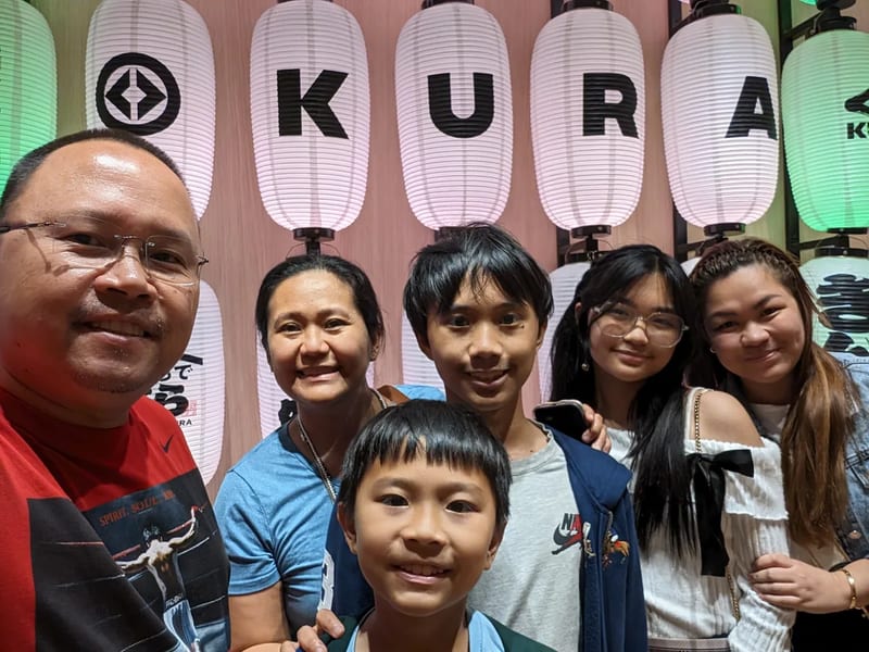 Family selfie in front of colored Kura Sushi Japanese lanterns in Osaka, Japan.
