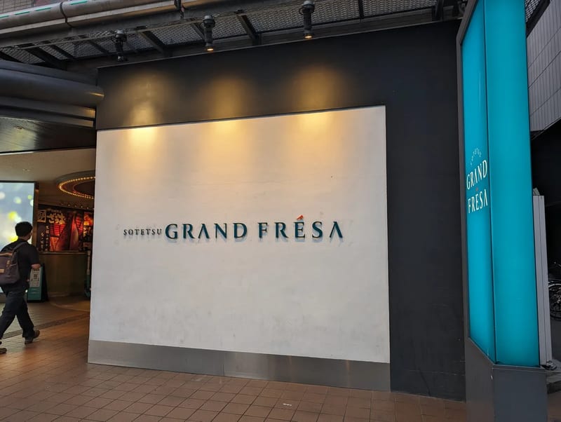 Exterior sign for Sotetsu Grand Fresa hotel with blue lettering in Osaka, Japan.