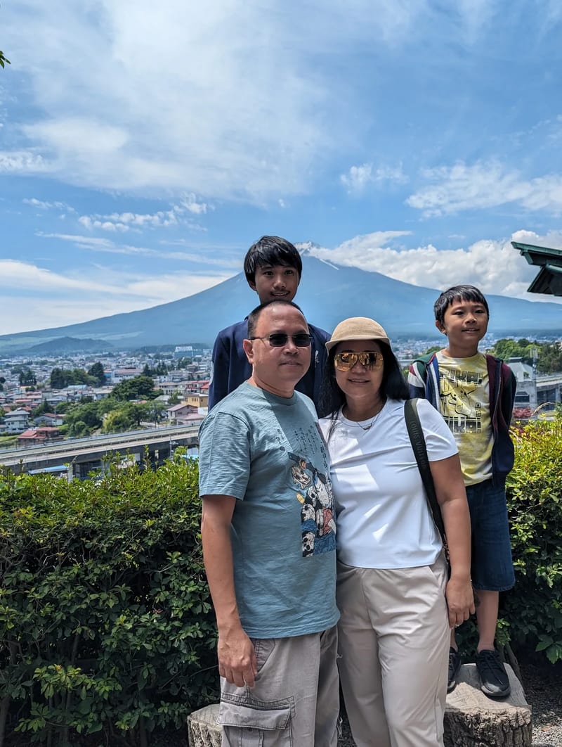 Family of four posing with Mount Fuji and town in background, Fujiyoshida, Yamanashi, Japan.