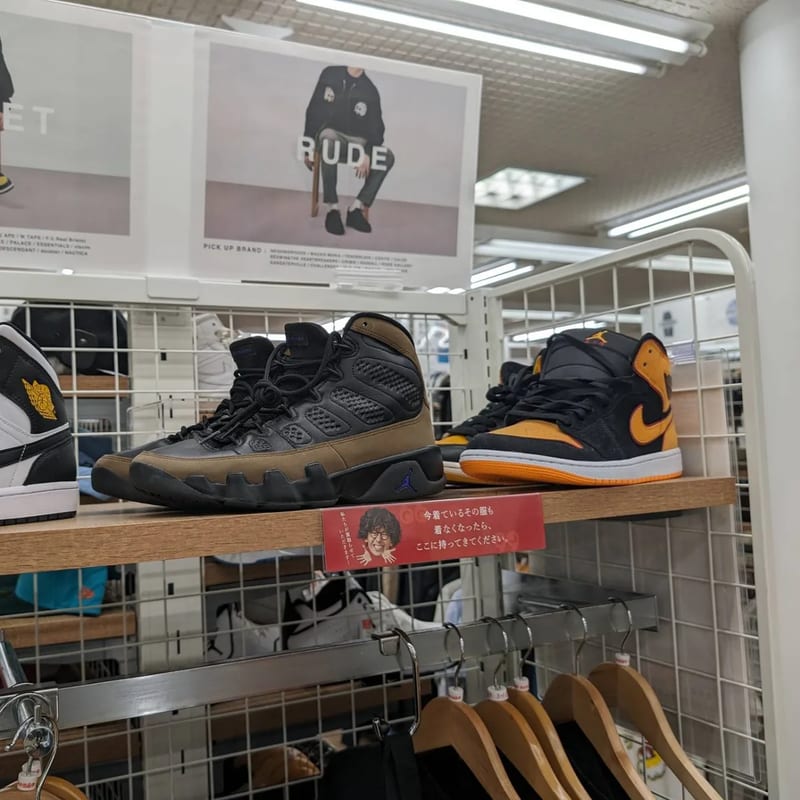 Black and brown, and black and orange high-top sneakers on a shelf at a Japanese second-hand store.