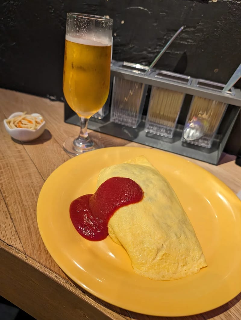 Omurice with ketchup heart — Tokyo, Japan. Good way to end a long day. Japanese omurice with a heart drawn in ketchup next to a beer, Tokyo, Japan.