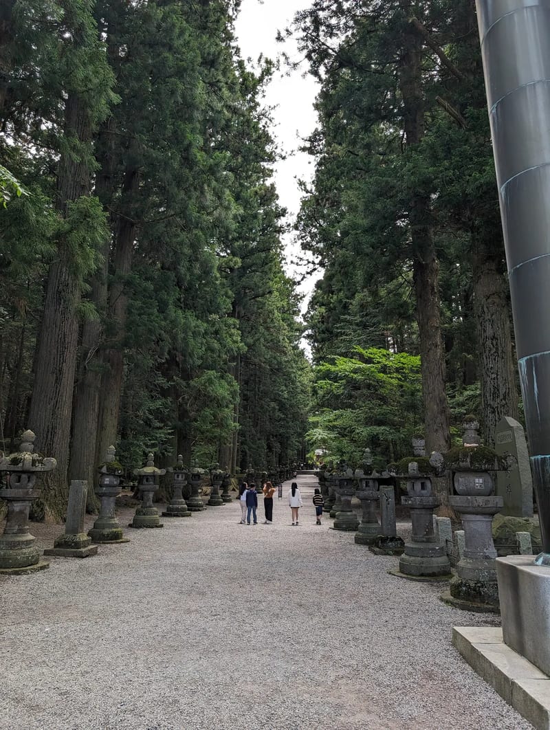 The approach path at Fuji Sengen-Jinja Shrine, lined with stone lanterns and cedar trees — Yamanashi, Japan Stone lanterns lining the path through tall cedar trees at Fuji Sengen-Jinja Shrine, Fujiyoshida, Yamanashi, Japan.