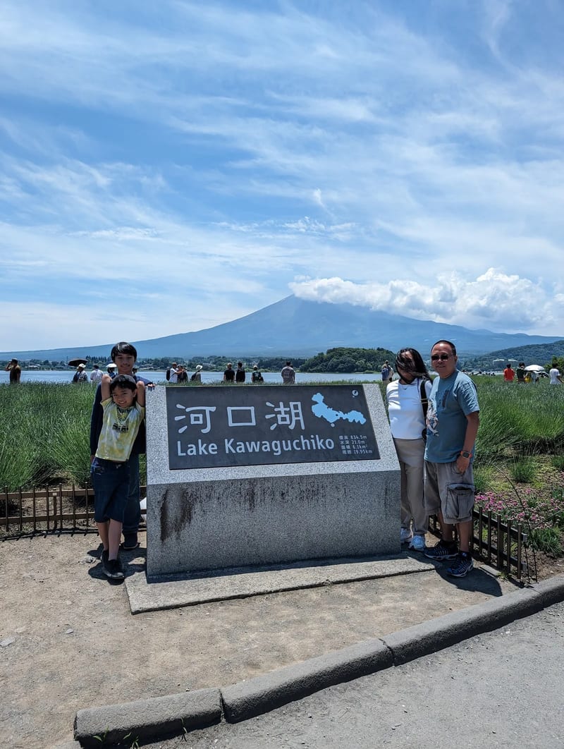 Family of four with Lake Kawaguchi-ko and Mount Fuji behind them, Fujikawaguchiko, Yamanashi, Japan.