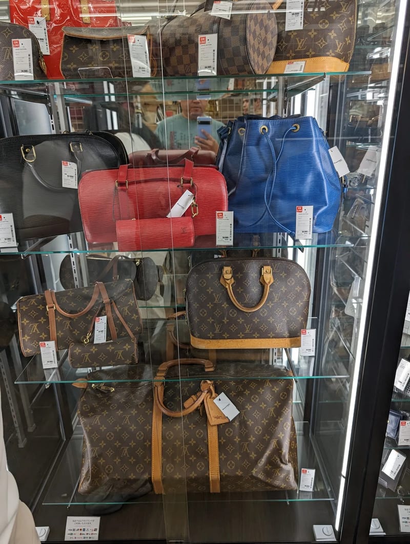 Colorful Louis Vuitton handbags on display at a Japanese resale store.