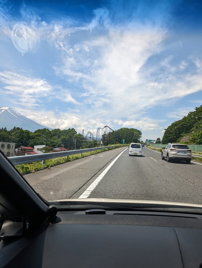 Mount Fuji and a roller coaster from a highway in Fujiyoshida, Yamanashi, Japan.