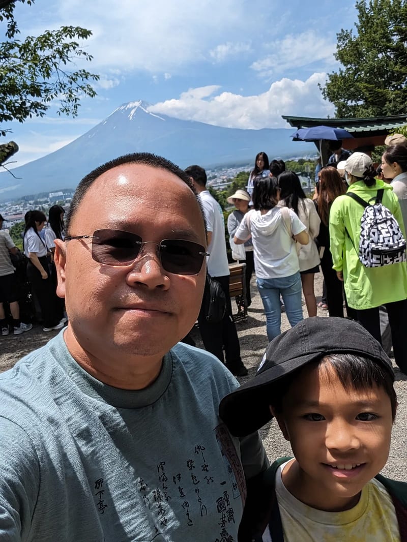 Selfie of man and son with Mount Fuji in background at Arakurayama Sengen Park, Yamanashi, Japan.
