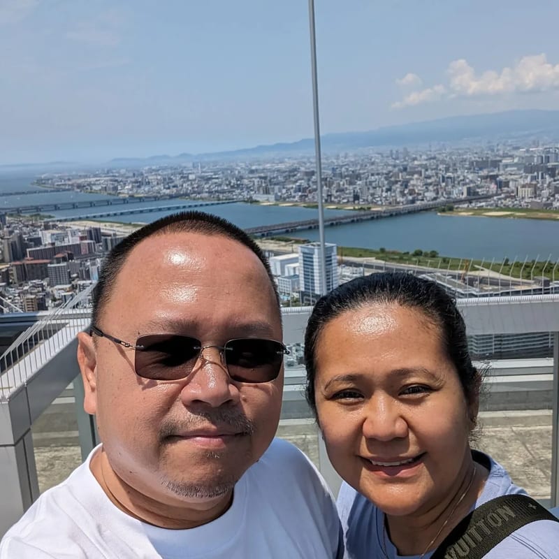 Couple selfie on the Umeda Sky Building rooftop with panoramic Osaka city view, Japan.