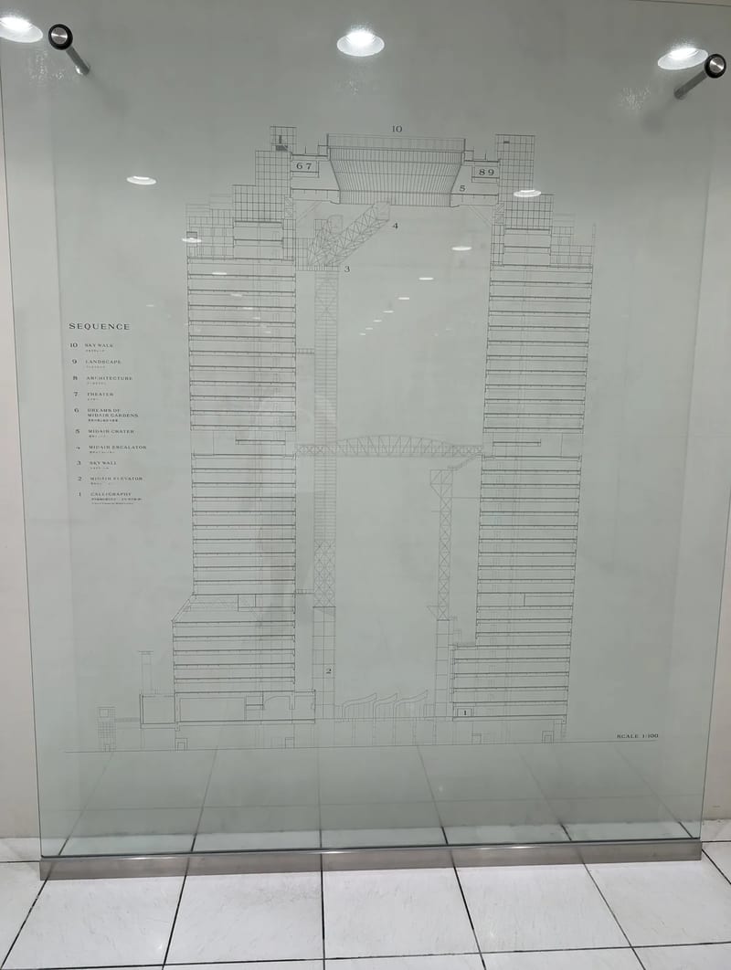 Man taking selfie at Umeda Sky Building interior with building blueprint display in Osaka, Japan.