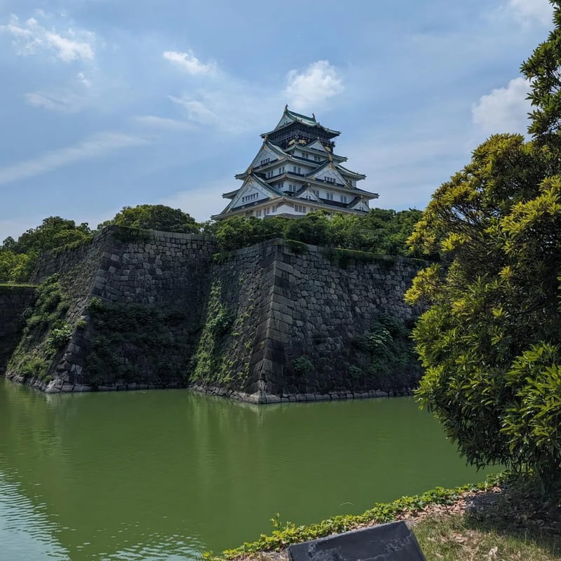 Corner view of Osaka Castle showing stone walls and green moat in Osaka, Japan.