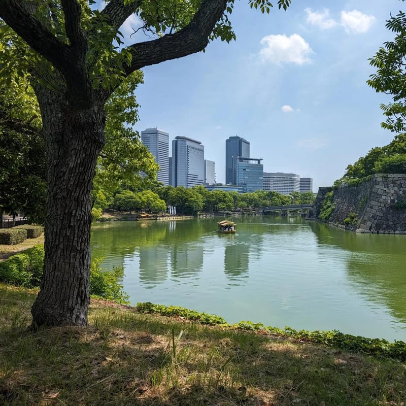 Osaka Castle moat with boat and city skyline visible in the distance, Osaka, Japan.