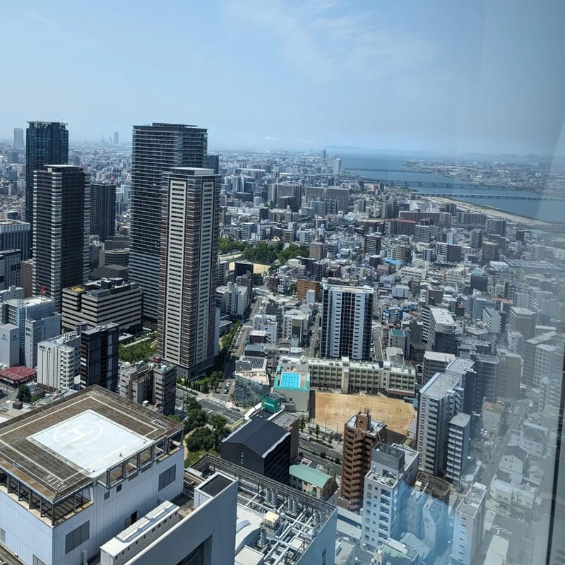 Panoramic Osaka cityscape from Umeda Sky Building rooftop showing river and mountains, Japan.