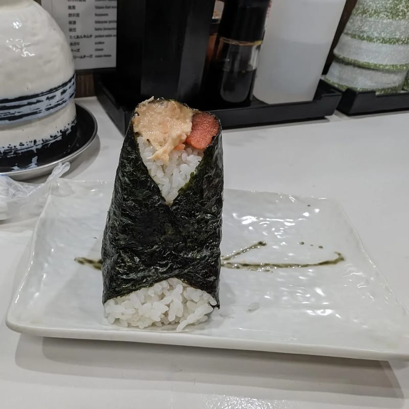 Single onigiri with pink roe and cream sauce on a white plate at Onigiri Gorichan in Osaka, Japan.