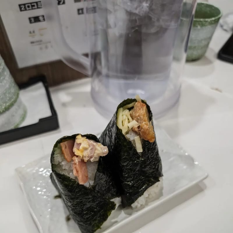 Two onigiri wrapped in nori seaweed on a white plate at Onigiri Gorichan in Osaka, Japan.