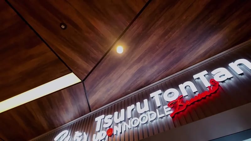 Tsuru Ton Tan Udon Noodle Brasserie neon sign with red lettering and warm wooden ceiling at Shibuya Sky, Shibuya, Tokyo, Japan.