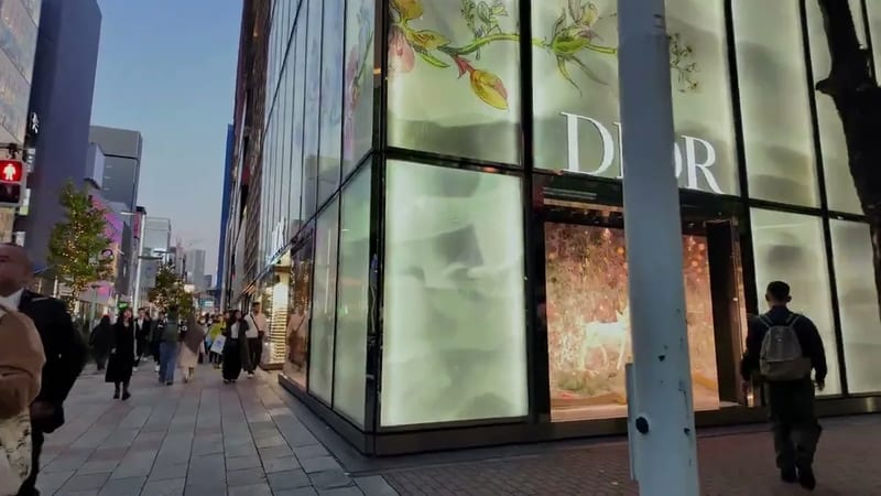 Exterior of the Dior luxury store in Ginza, Tokyo, Japan, with illuminated floral displays and pedestrians at dusk.