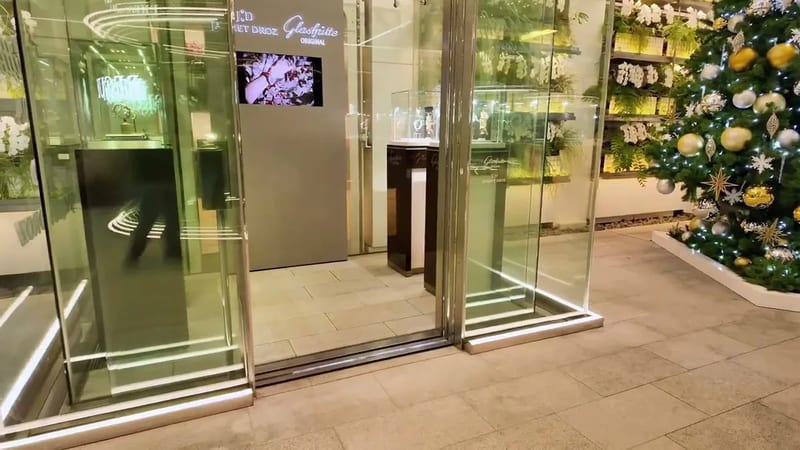 Luxury store interior in Ginza, Tokyo, Japan, with glass display cases, watches, jewelry, and a Christmas tree.