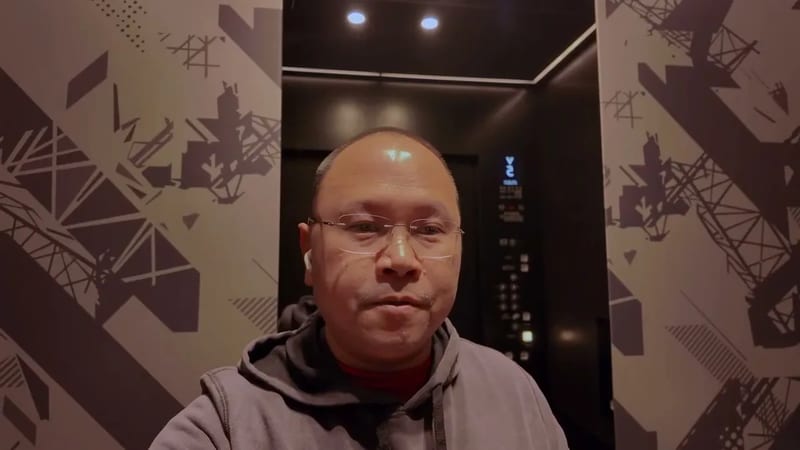 Man in glasses and earbuds taking a selfie in an elevator at Tokyo Skytree, Tokyo, Japan.