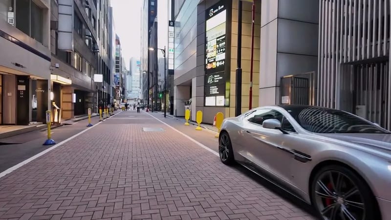 Sleek silver sports car parked on a brick-paved street in Ginza, Tokyo, Japan, lined with modern buildings.