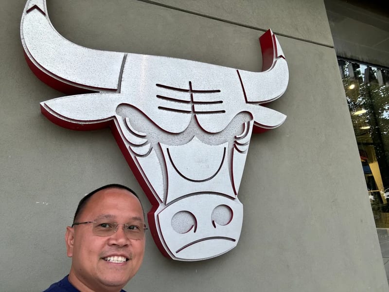 Man smiling in close-up selfie with Chicago Bulls logo at the Madhouse Team Store, United Center, Chicago, Illinois